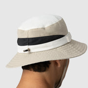 Beige bucket hat with a black mesh band worn by a person on a white background
