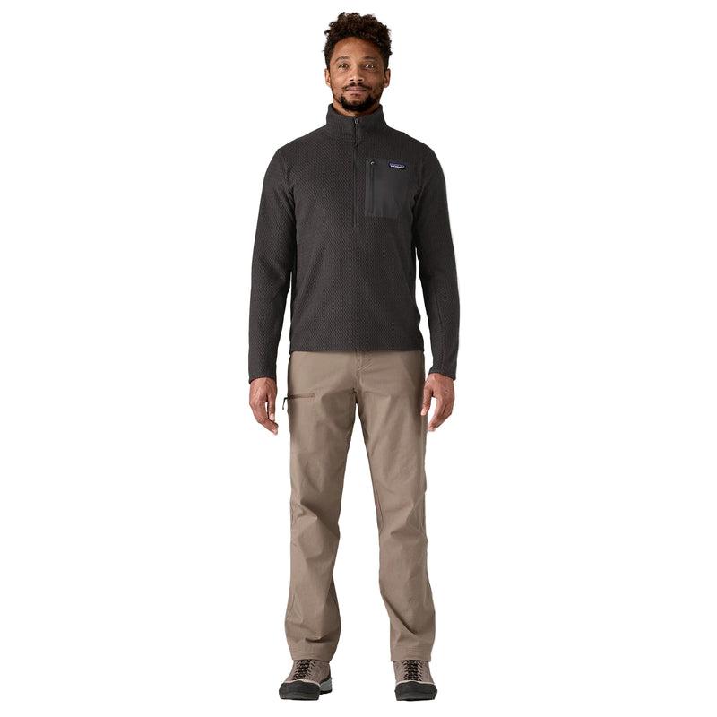 Man wearing a dark gray fleece jacket and beige pants on a white background