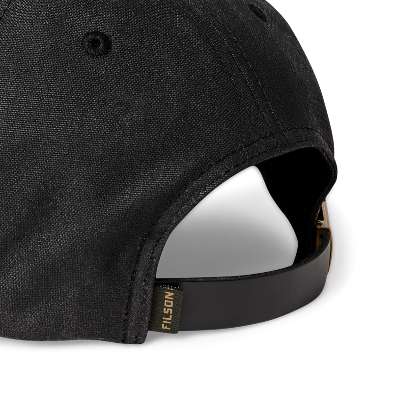 Close up back view of a black baseball cap featuring a Filson logo against a white background. 