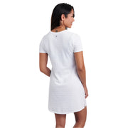 Woman wearing a white t-shirt dress on a white background, shown from behind
