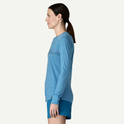 A person from the side wearing a blue long sleeve shirt on a white background