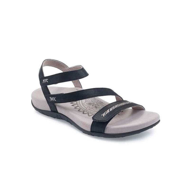 A white sandal with a black bottom and black straps on a white background