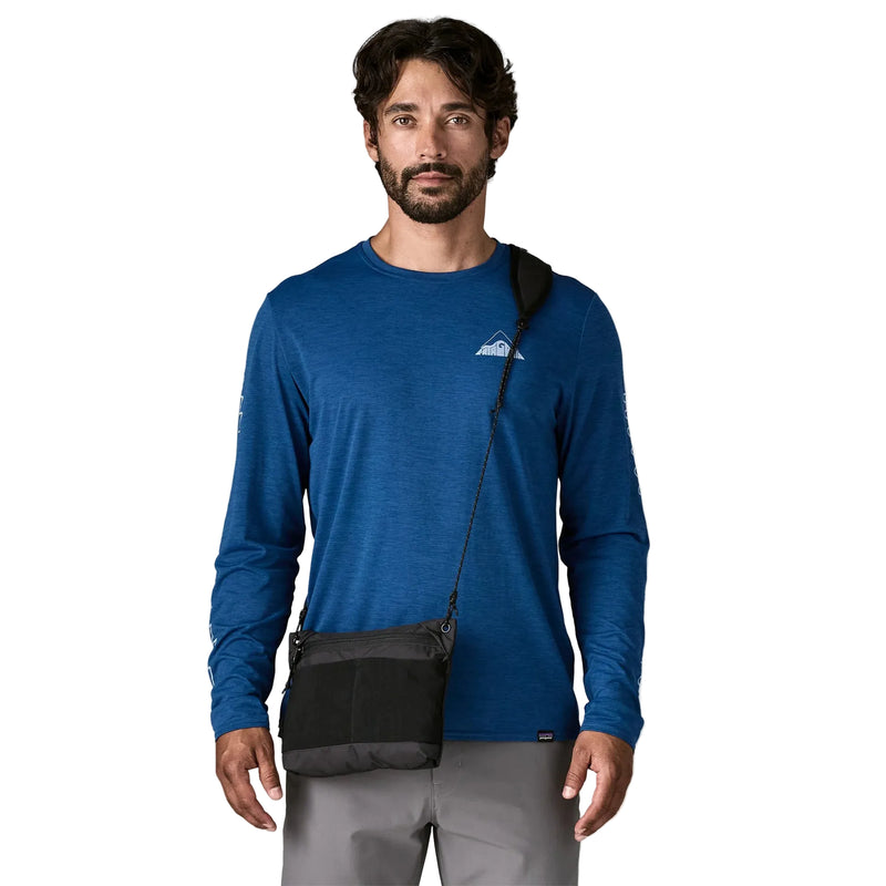 A person wearing a black cross body bag on a white background