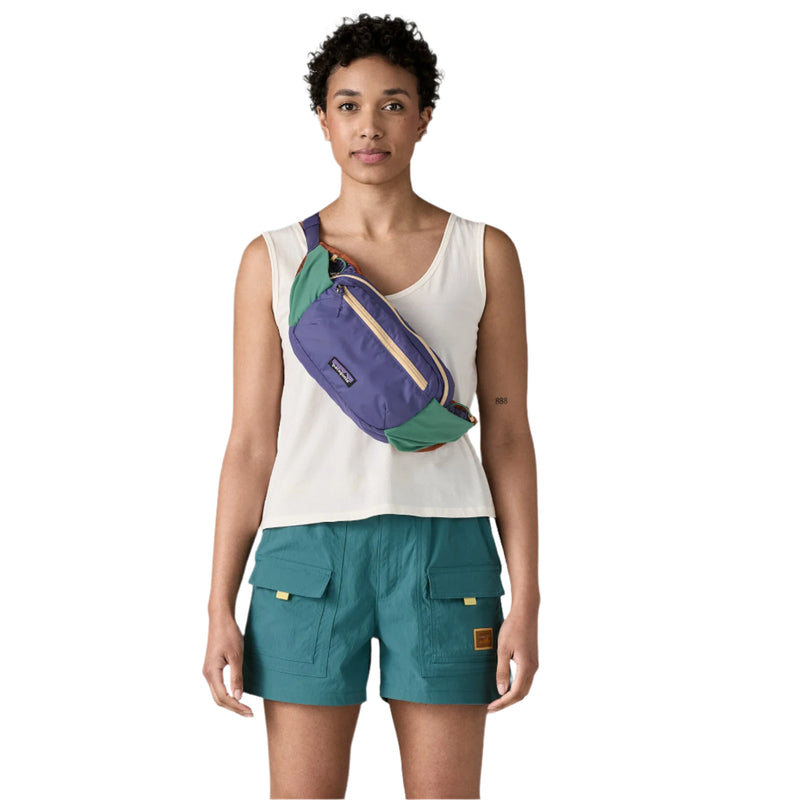 Woman wearing a colorful waist bag on a plain background