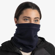 Person wearing a navy blue neck gaiter over a black jacket on a white background