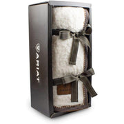 White fuzzy throw blanket wrapped in a ribbon in a display box against a white background. 