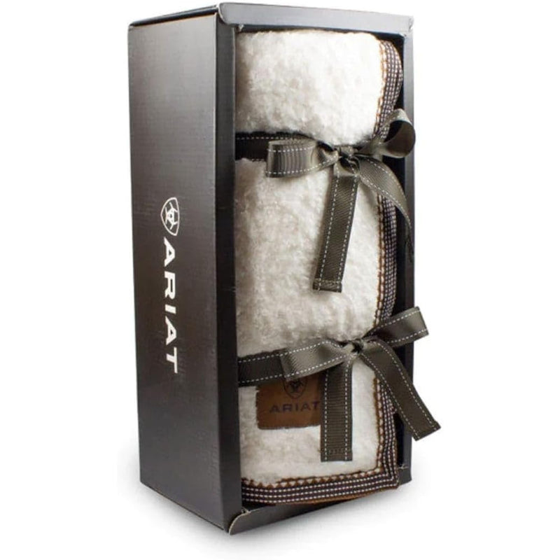 White fuzzy throw blanket wrapped in a ribbon in a display box against a white background. 