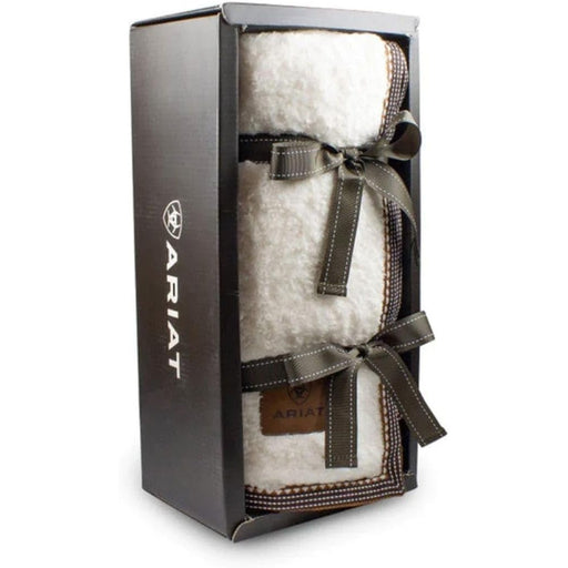 White fuzzy throw blanket wrapped in a ribbon in a display box against a white background. 
