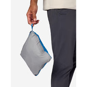 A person wearing dark gray Marmot pants holds a small gray and blue zippered pouch against a clean white background.
