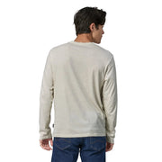 Man wearing a light beige long-sleeve shirt and blue jeans on a white background