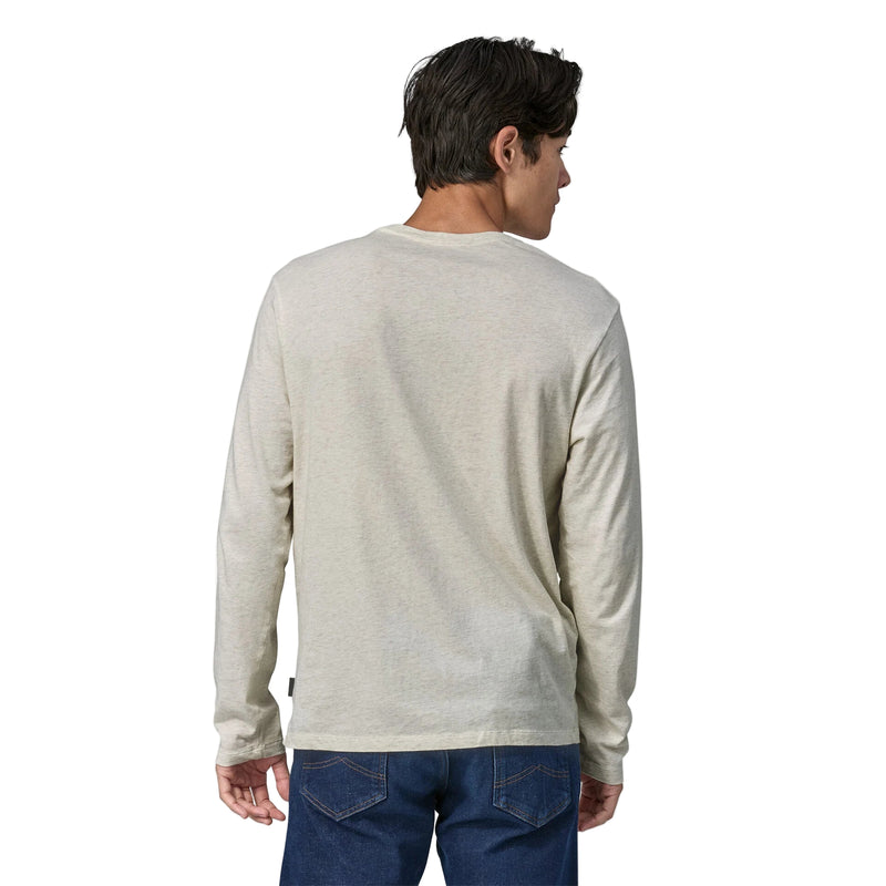 Man wearing a light beige long-sleeve shirt and blue jeans on a white background