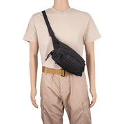 A black crossbody sling bag worn by a mannequin dressed in a beige t-shirt, khaki pants, and a tan belt against a plain white background.