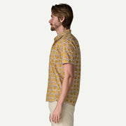 Side view of a man wearing a white and yellow patterned button down shirt on a white background.