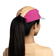 Person wearing a two-tone cap with beige and pink colors on a white background