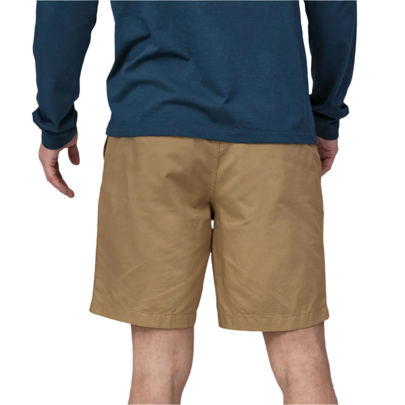 Person wearing a blue long-sleeve shirt and tan shorts on a white background