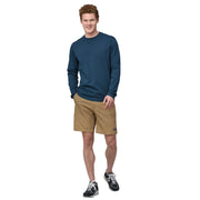 Man wearing a blue long-sleeve shirt and beige shorts on a white background