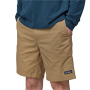 Person wearing tan shorts with a Patagonia logo on a white background