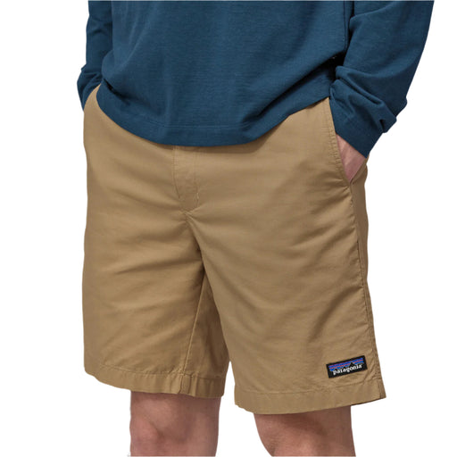 Person wearing tan shorts with a Patagonia logo on a white background