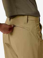 A person wearing tan cargo shorts unzipping the back pocket on a white background