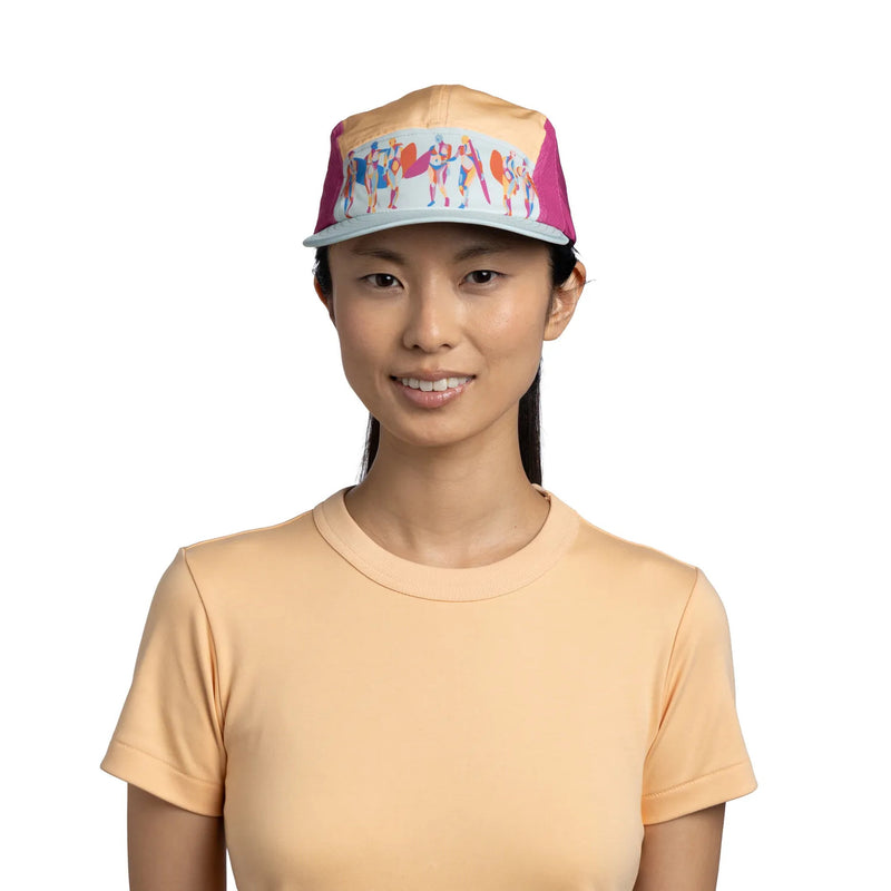 Woman wearing a colorful cap and peach shirt on a white background