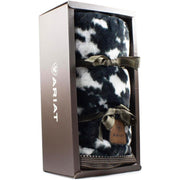 Black and white cow print throw blanket wrapped in a ribbon and in a display box against a white background. 