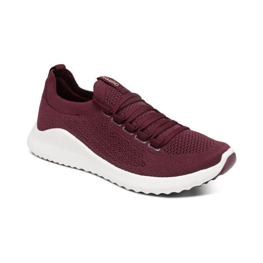 A maroon shoe with a white bottom on a white background