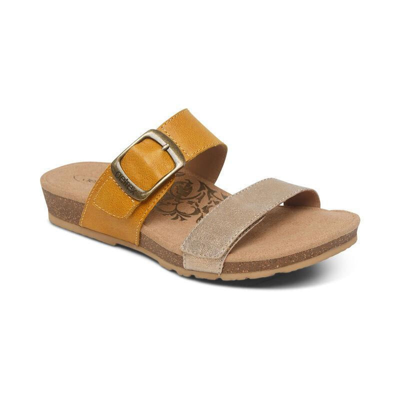 A tan sandal with a yellow strap on a white background