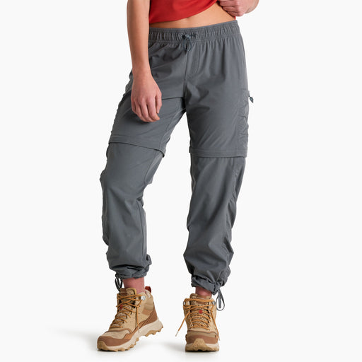 Person wearing gray hiking pants with a red top and tan boots on a white background
