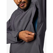 Close-up of a man wearing a dark gray waterproof jacket, opening the armpit zipper to reveal a blue lining.