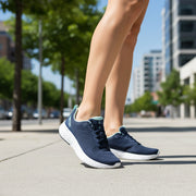 Woman wearing navy running shoe with white sole on an urban sidewalk