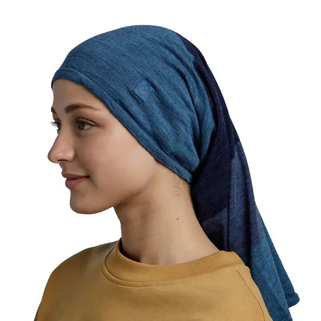 Woman wearing a blue buff as a headwrap against a white background. 