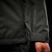 Close-up of a black jacket with a brand logo on the sleeve against a dark background