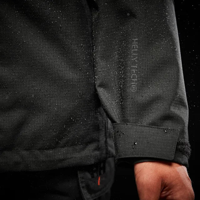Close-up of a black jacket with a brand logo on the sleeve against a dark background