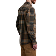 Man wearing a plaid shirt and brown pants on a white background