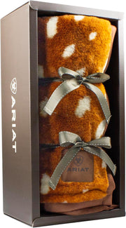 Brown blanket with white polka dots wrapped in a bow in in a case against a white background. 