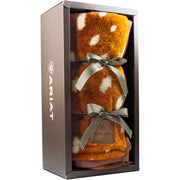 Brown blanket with white polka dots wrapped in a bow in in a case against a white background. 