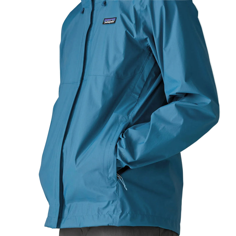 A person wearing a blue rain jacket with their hands in the pockets on a white background