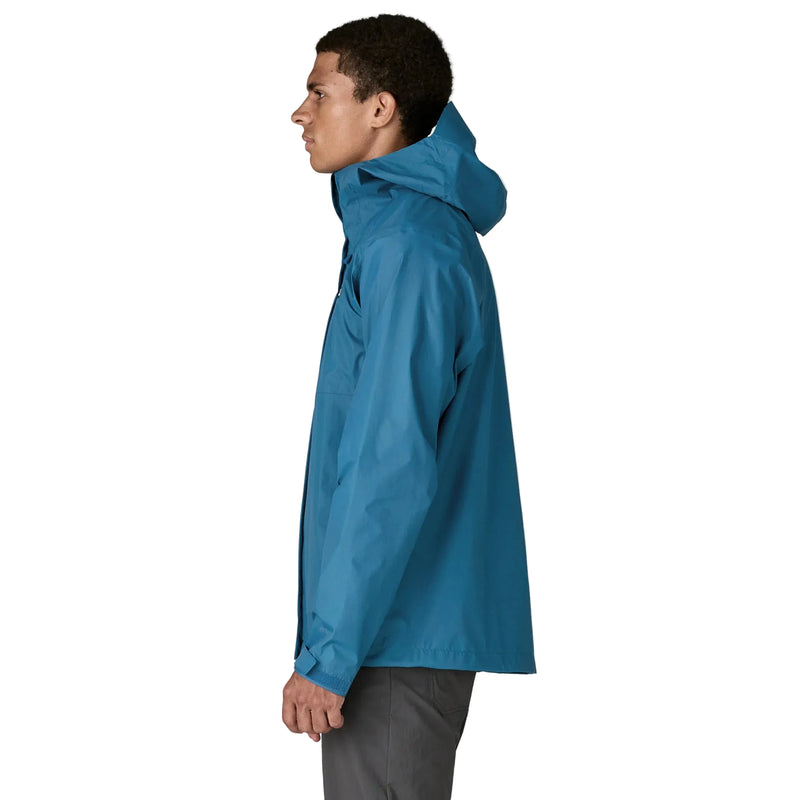 A person from the side wearing a blue rain jacket on a white background