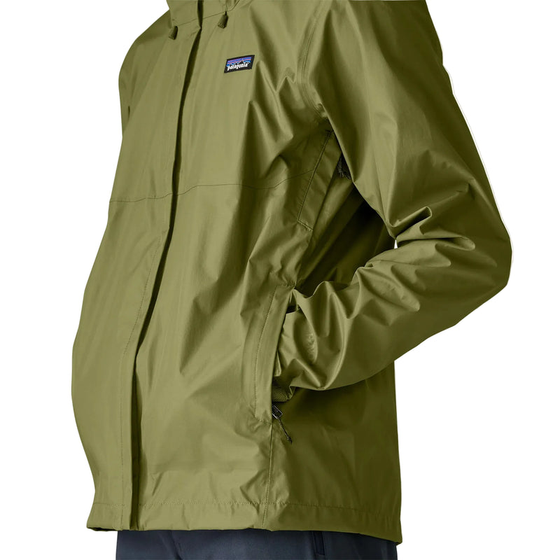 A person wearing a green rain jacket with their hands in the pockets on a white background