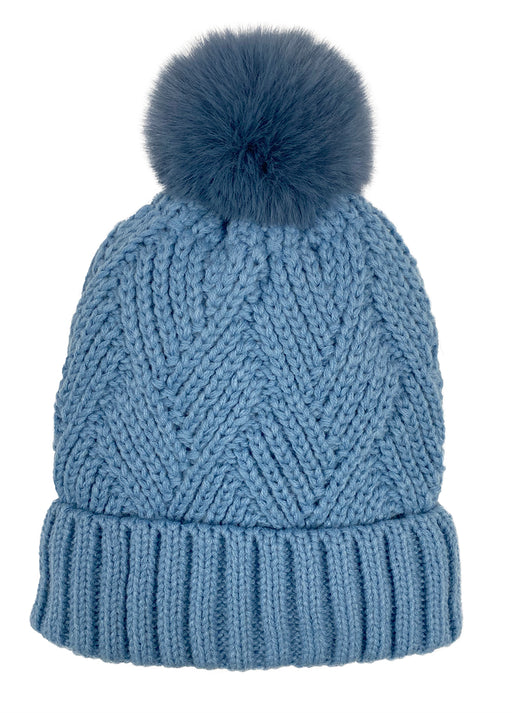Sky blue knit pom pom beanie against a white background. 