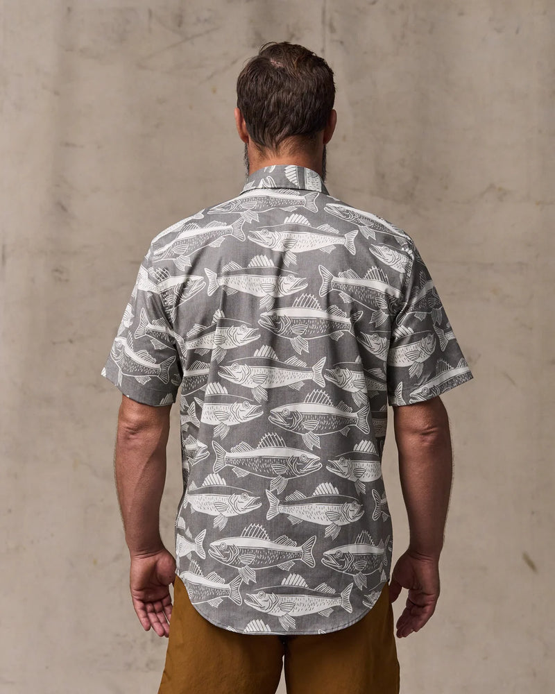 Man wearing a gray shirt with fish pattern against a plain background