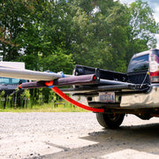 Red extender for boat attached to the back of a pickup truck with trees in the background.