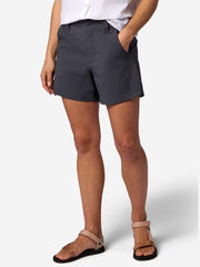 A person wearing navy blue cargo shorts with hand in their pocket on a white background