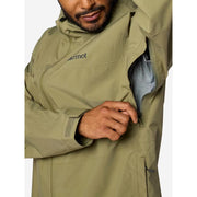 A close-up of a man wearing a Marmot olive green waterproof jacket, demonstrating a side zippered pocket that opens to reveal a striped shirt underneath.