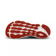 The bottom of a black and red running shoe on a white background