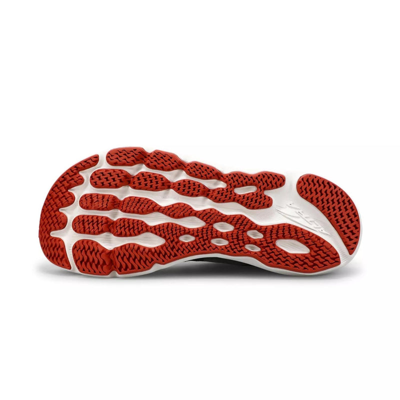 The bottom of a black and red running shoe on a white background