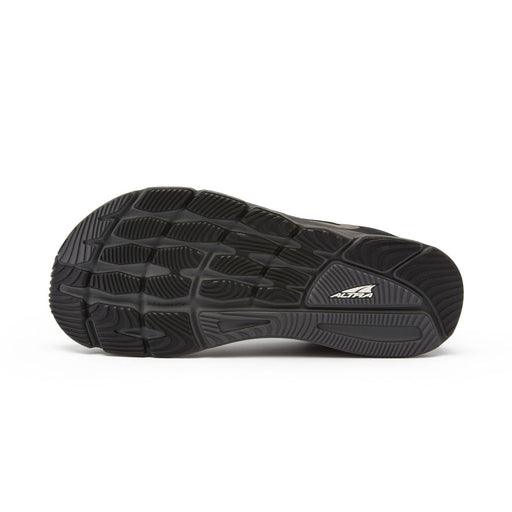 The bottom of a black running shoe on a white background