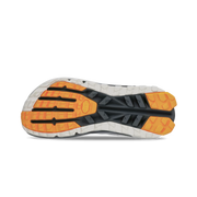 Bottom view of a hiking shoe with a black, white, and orange tread against a white background. 