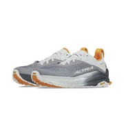 Side view of a pair of gray hiking shoes with orange and white accents against a white background. 