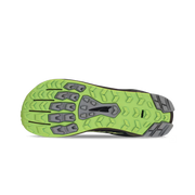 Bottom view of a black shoe. The tread has a lime green and grey color against a white background. 